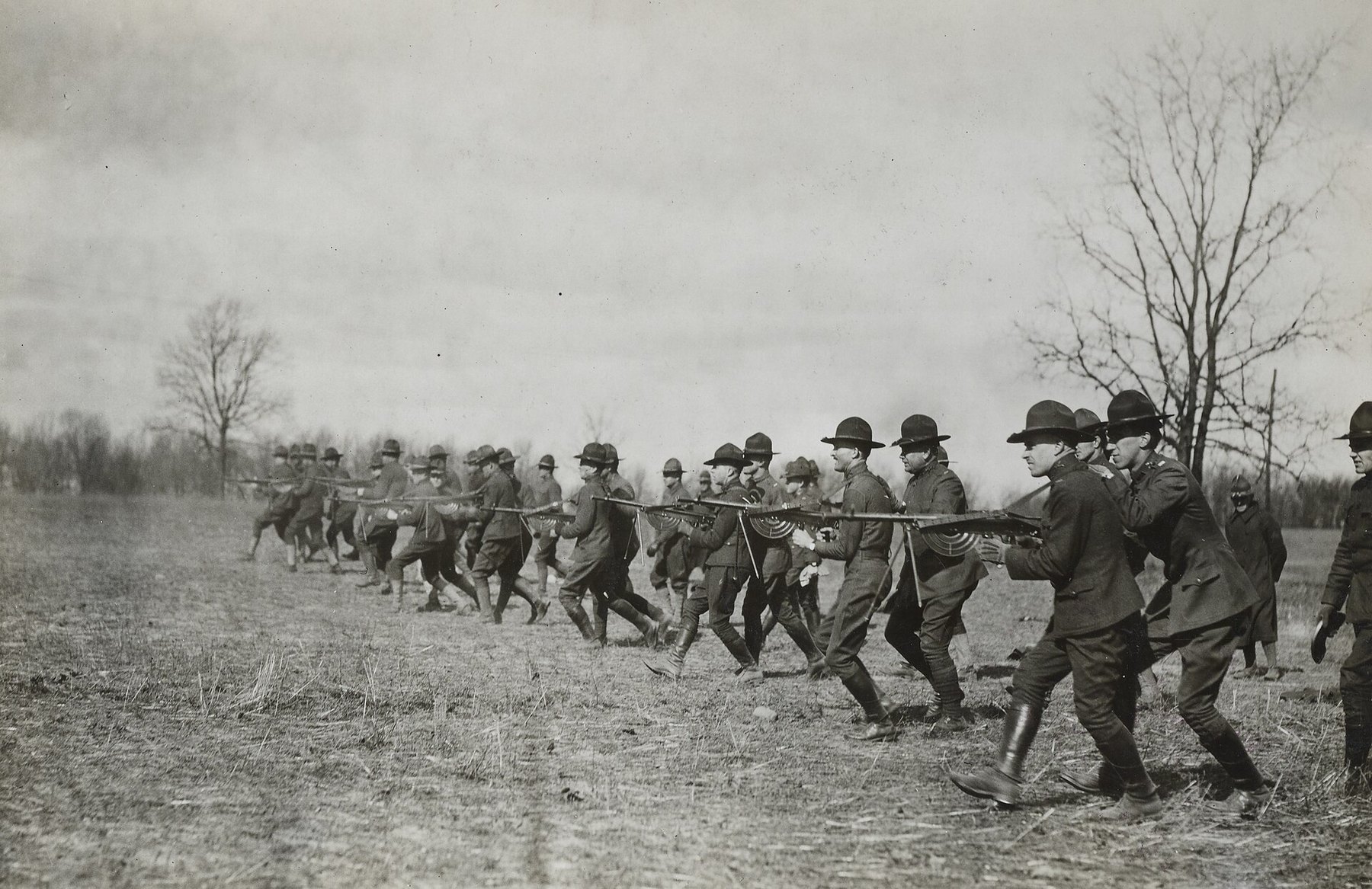 Figure 1 — Chauchat practice at Camp Custer, Michigan: a line of soldiers in campaign hats walks forward firing Chauchats from the hip, the drill that the French 1916 instruction calls firing while marching. …