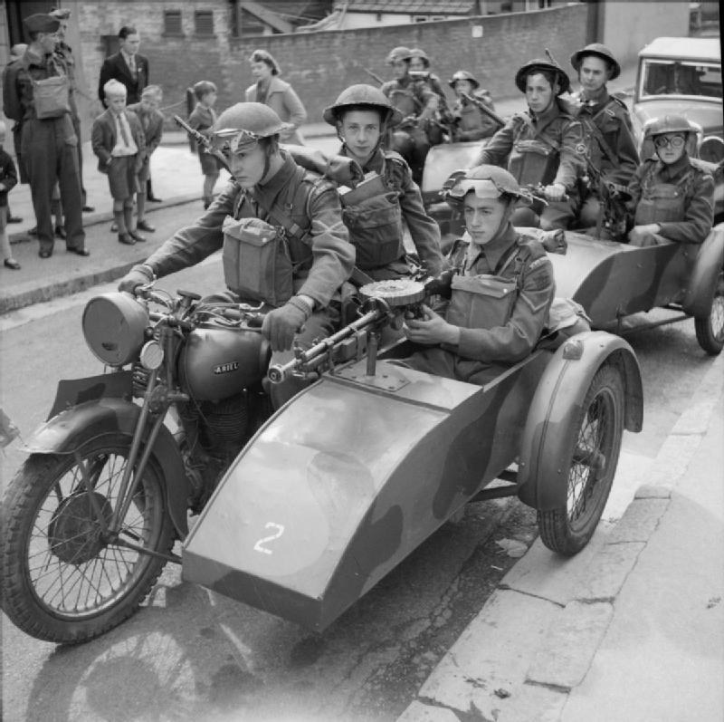 Figure 1 — Home Guard soldiers on motorcycle sidecar combinations fitted with Lewis guns during an exercise near Exeter, 10 August 1941. The gun on the leading sidecar is an aircraft-pattern gun, with no radi…