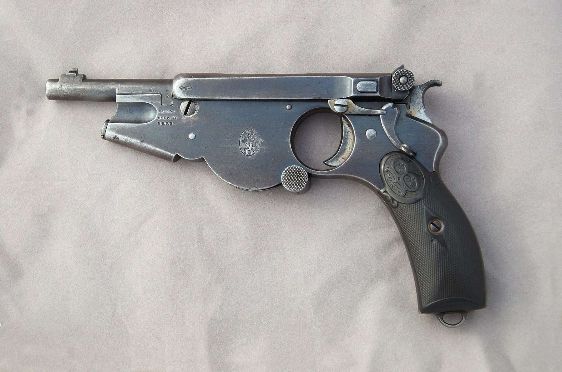 Figure 5 — The conventional No. 2: serial 1221, left side, with the trigger in a ring guard and the oval trademark on the frame in front of it. Self Loader, CC BY 4.0, via Wikimedia Commons.