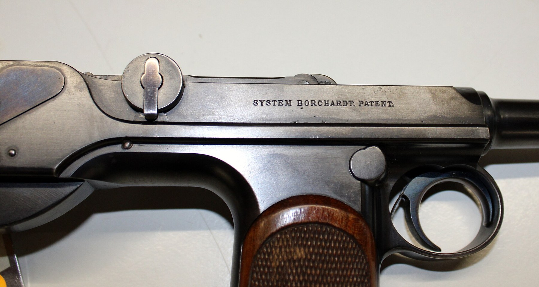 Figure 14 — The right side of the Loewe pistol's action, showing the single-line "SYSTEM BORCHARDT. PATENT." marking and, at the left of the frame, the rear housing with its fire-blued cover plate. The right s…