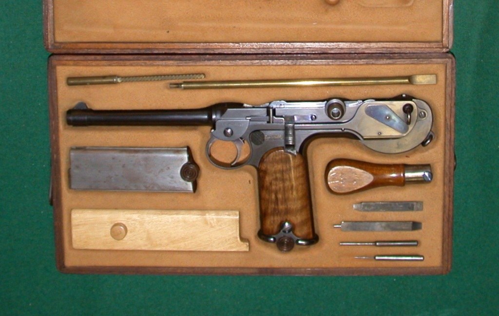 Figure 8 — A cased Borchardt outfit as photographed by its owner: the pistol, a spare magazine, cleaning rod, tools, oil bottle and the magazine-shaped wooden barring block. The factory sold the pistol as a k…