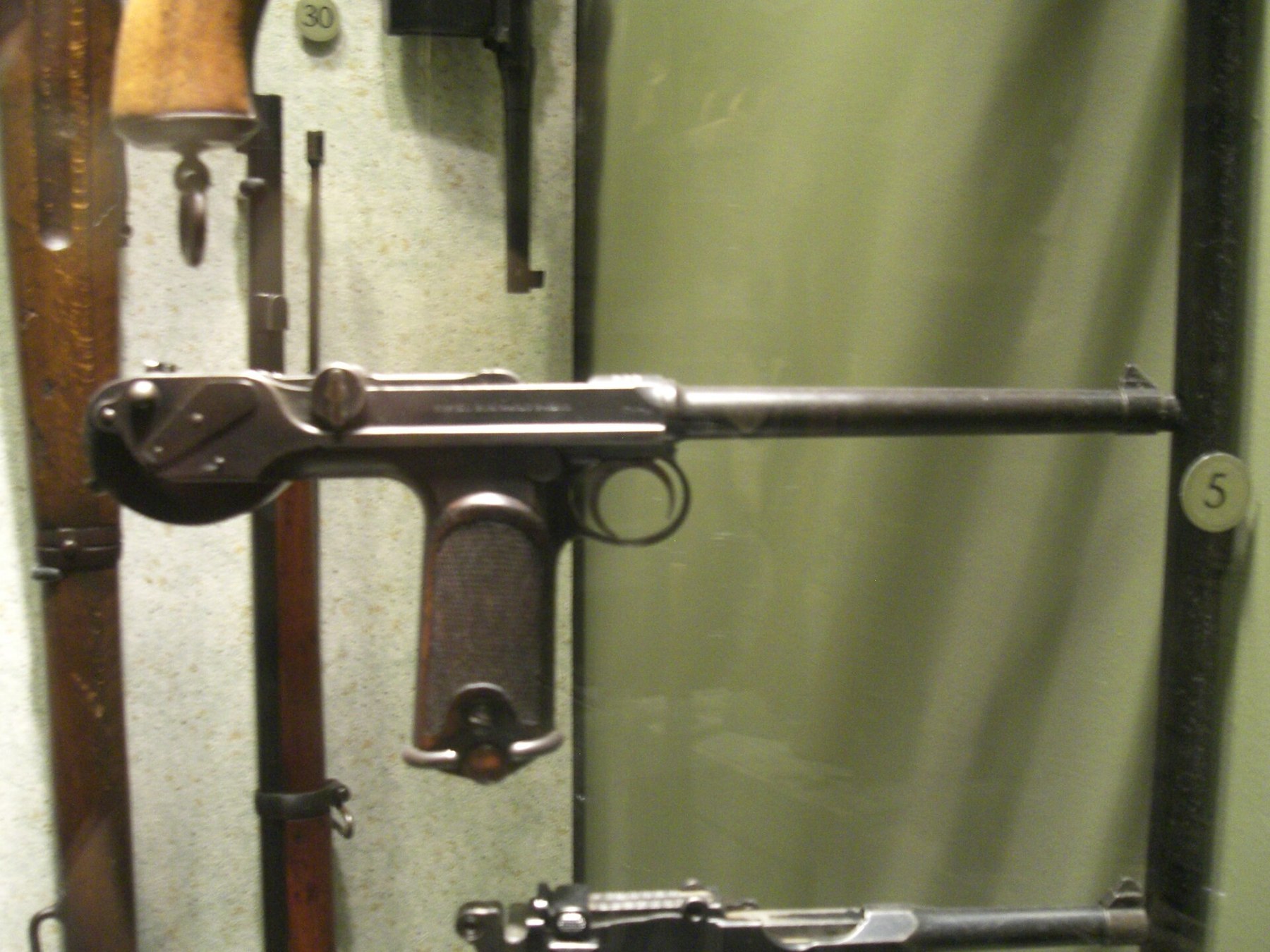 Figure 7 — The same unidentified display, wider: a C-93 hung in a case with other arms. Its single-line right-side marking identifies it as Loewe pattern.