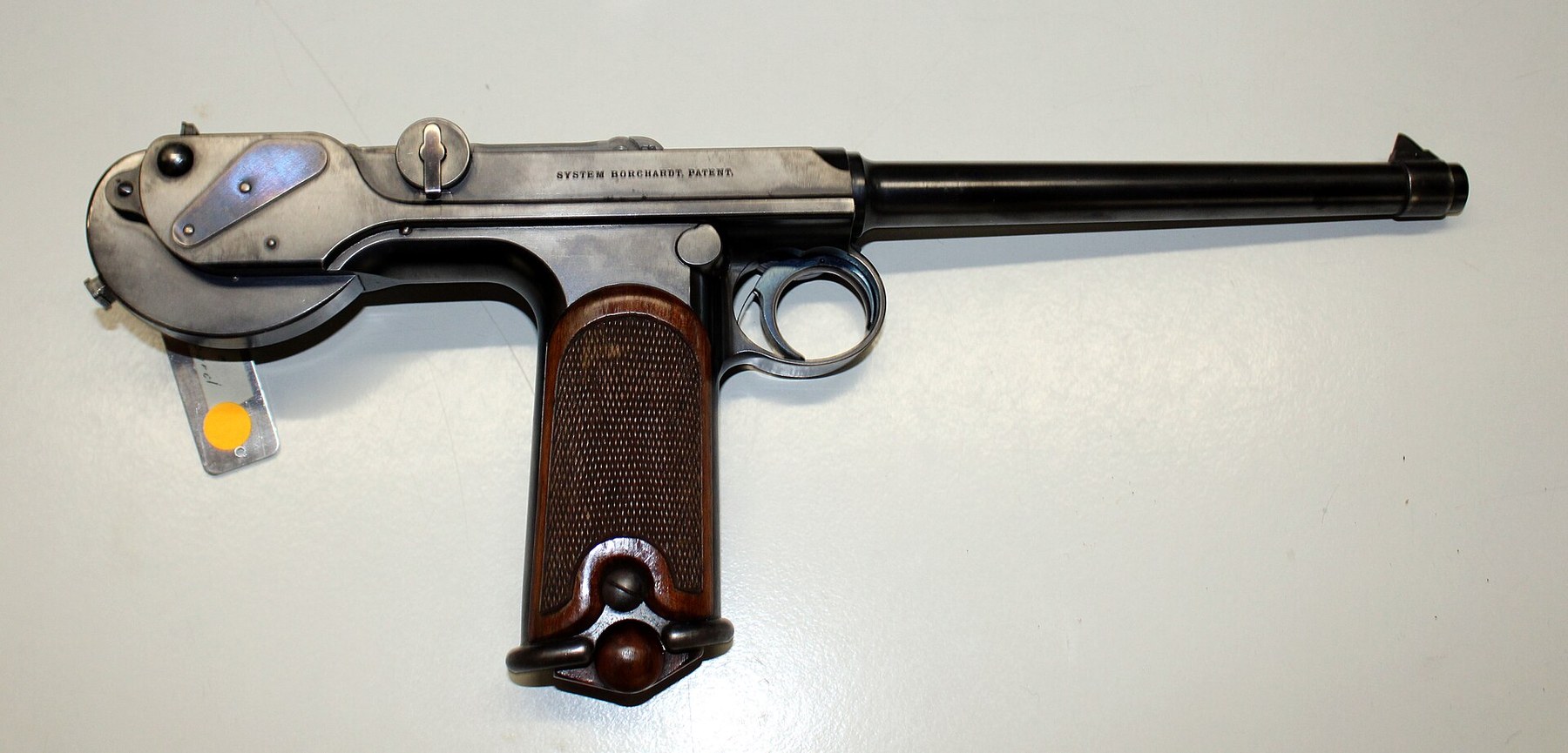 Figure 2 — A Loewe C-93, right side. The spring box, with its single screw, hangs from two ears at the rear of the grip; the fire-blued plate covers the right end of the connecting pin; the knob on the left o…