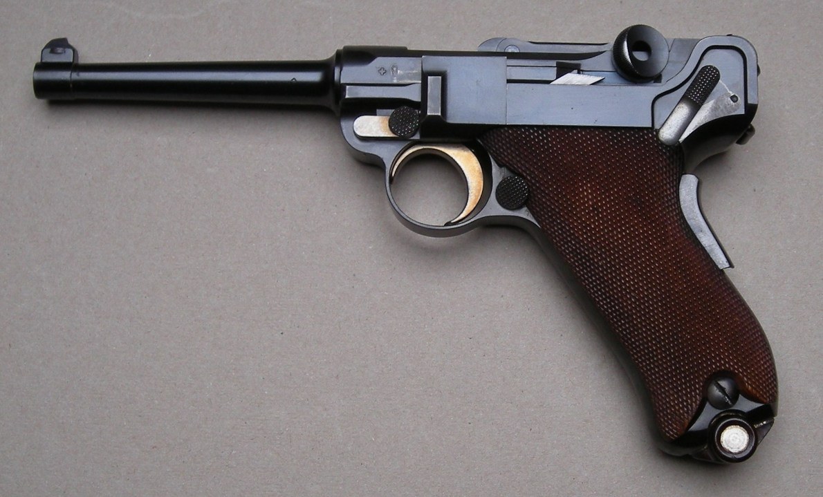 Figure 11 — A commercial Luger of the 1900 pattern. The grip safety in the back strap and the flat leaf spring inside the grip are the 1900 arrangement; the English encyclopaedia account of the Luger records t…