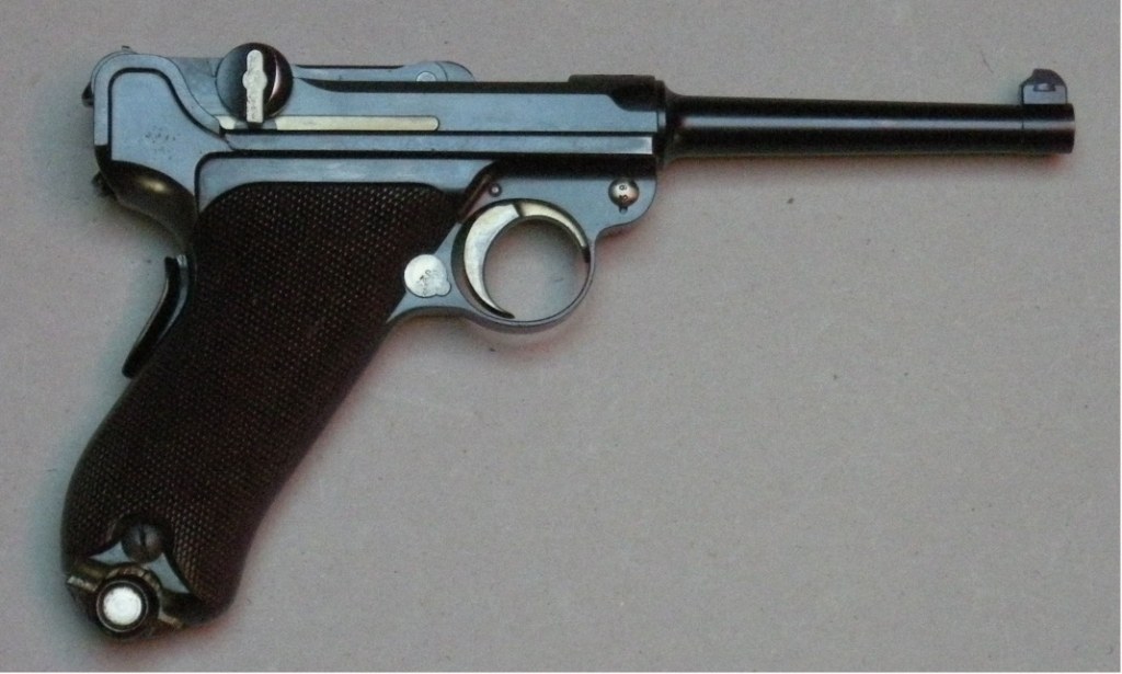 Figure 5 — The Swiss Pistole 1900, the first adopted descendant of the C-93. The spring housing has disappeared into the grip, the grip is raked, the toggle knobs are on the outside of the rear link where the…