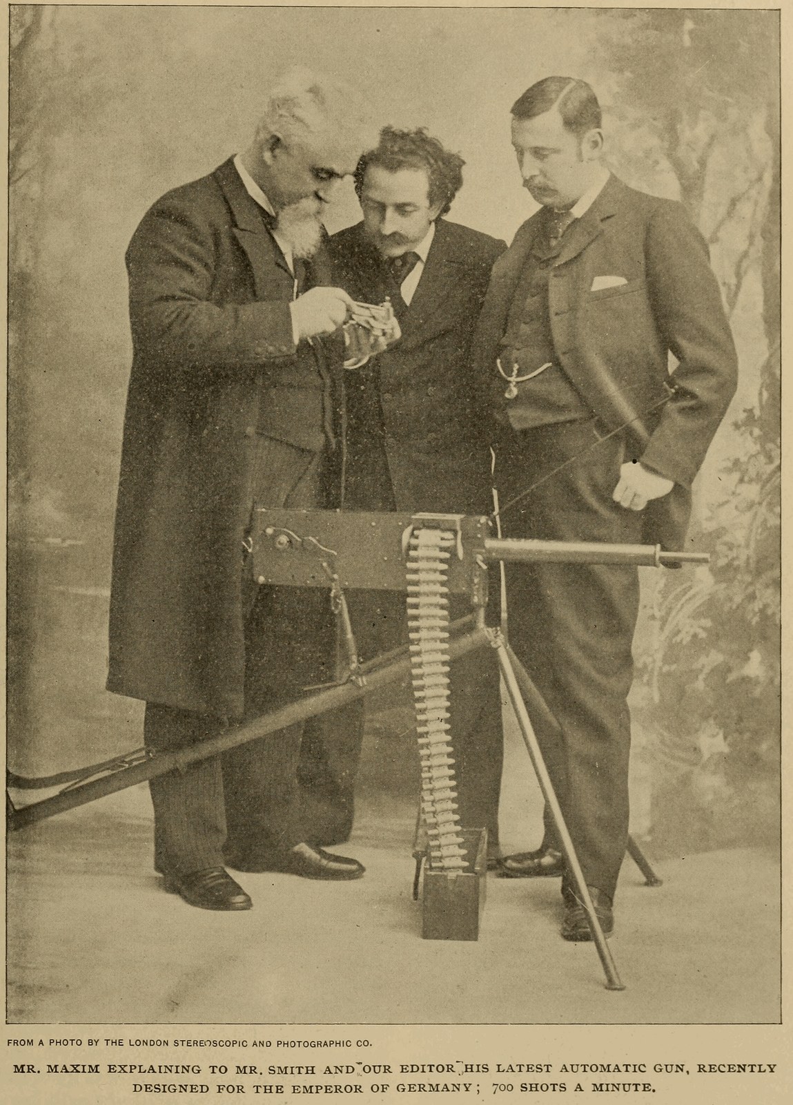 Figure 10 — Hiram Maxim demonstrating one of his automatic guns to two visitors, from Cassier's Magazine, April 1895. The caption describes the gun as "recently designed for the Emperor of Germany". Maxim's re…