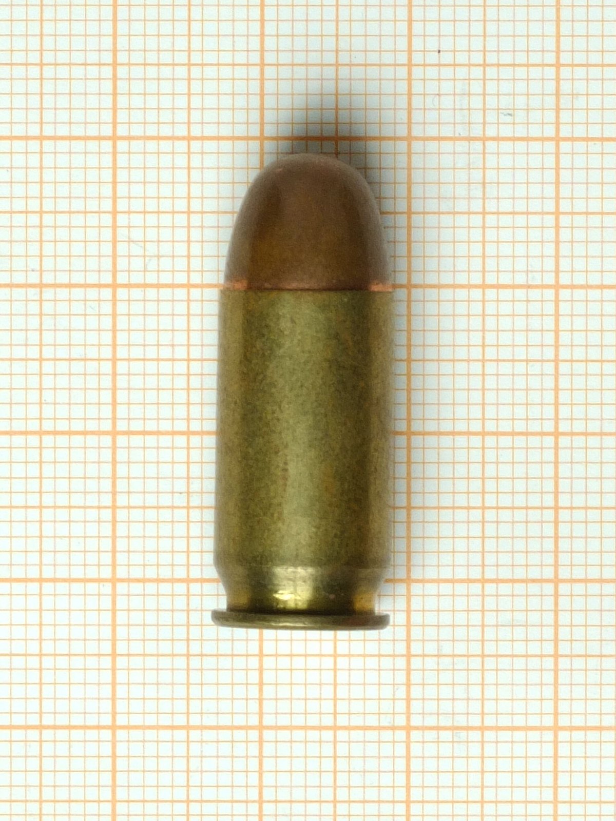 Figure 3 — A .45 ACP cartridge with a full-metal-jacket round-nose bullet, photographed on millimetre graph paper.