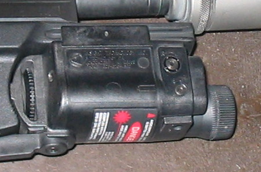 Figure 9 — The aiming module on a commercial Mark 23, showing how the Mk 23's accessory interface works: the module rides the frame's grooves and is held by a knurled screw into the trigger guard's threaded i…
