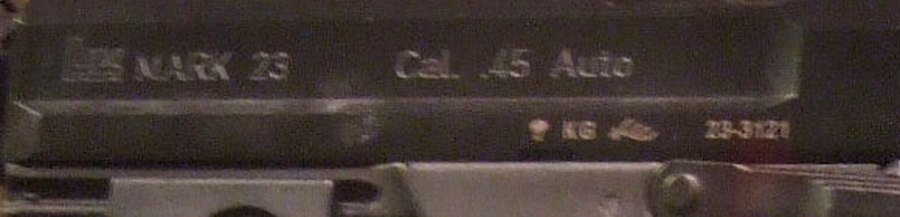 Figure 12 — The left side of a commercial Mark 23's slide: the H&K logo, "MARK 23" and "Cal. .45 Auto"; below, a proof-house mark, the code KG, an eagle device and the serial 23-3121. Enlarged from the Commons…
