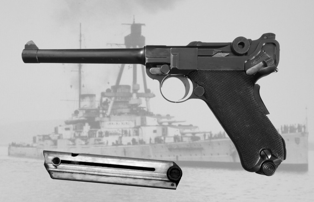 Figure 6 — A Navy pistol of the 1904 pattern with its magazine, set by the photographer against a period photograph of a German warship. The six-inch barrel, the rear sight on the rear toggle link and the gri…