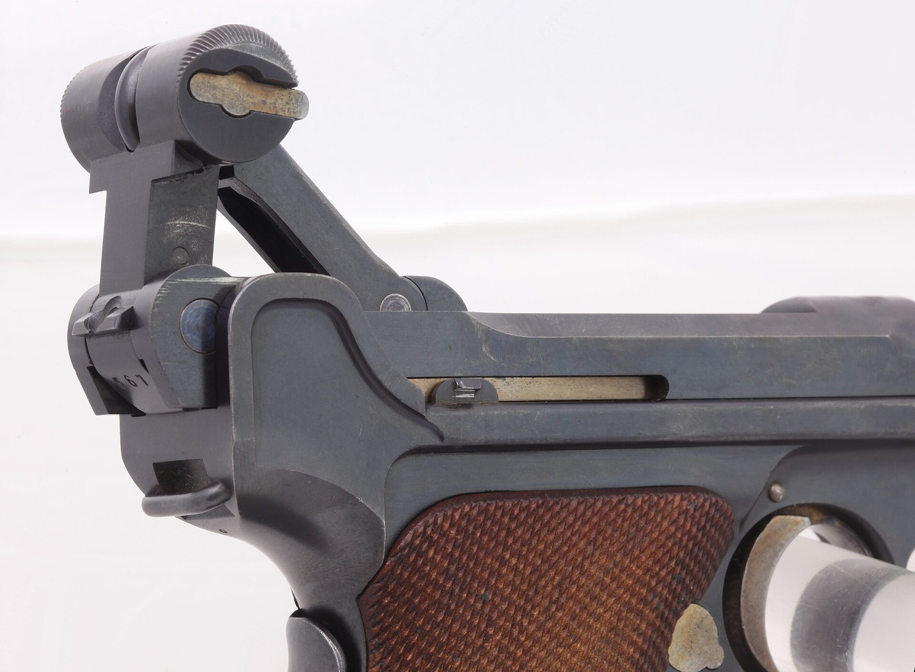 Figure 3 — The frame's ramp and the toggle knob of a Luger from the Paul Regnier collection in Lausanne, toggle raised. The curved face of the frame rising behind the knob is the ramp; the knob's flat inner c…