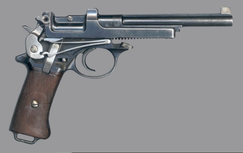 Figure 2 — The same pistol from the right with the cover removed: the V mainspring, its lower arm on the hammer and its upper arm on the cam under the slide. Photograph: Wesley Terrell, CC BY-SA 3.0, via Wiki…