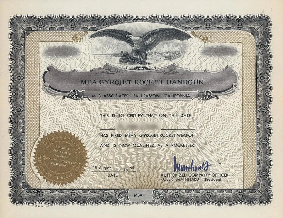 Figure 4 — An MBA "Gyrojet Rocket Handgun" certificate: "This is to certify that on this date ... has fired MBA's Gyrojet rocket weapon and is now qualified as a rocketeer", signed for the company by Robert M…