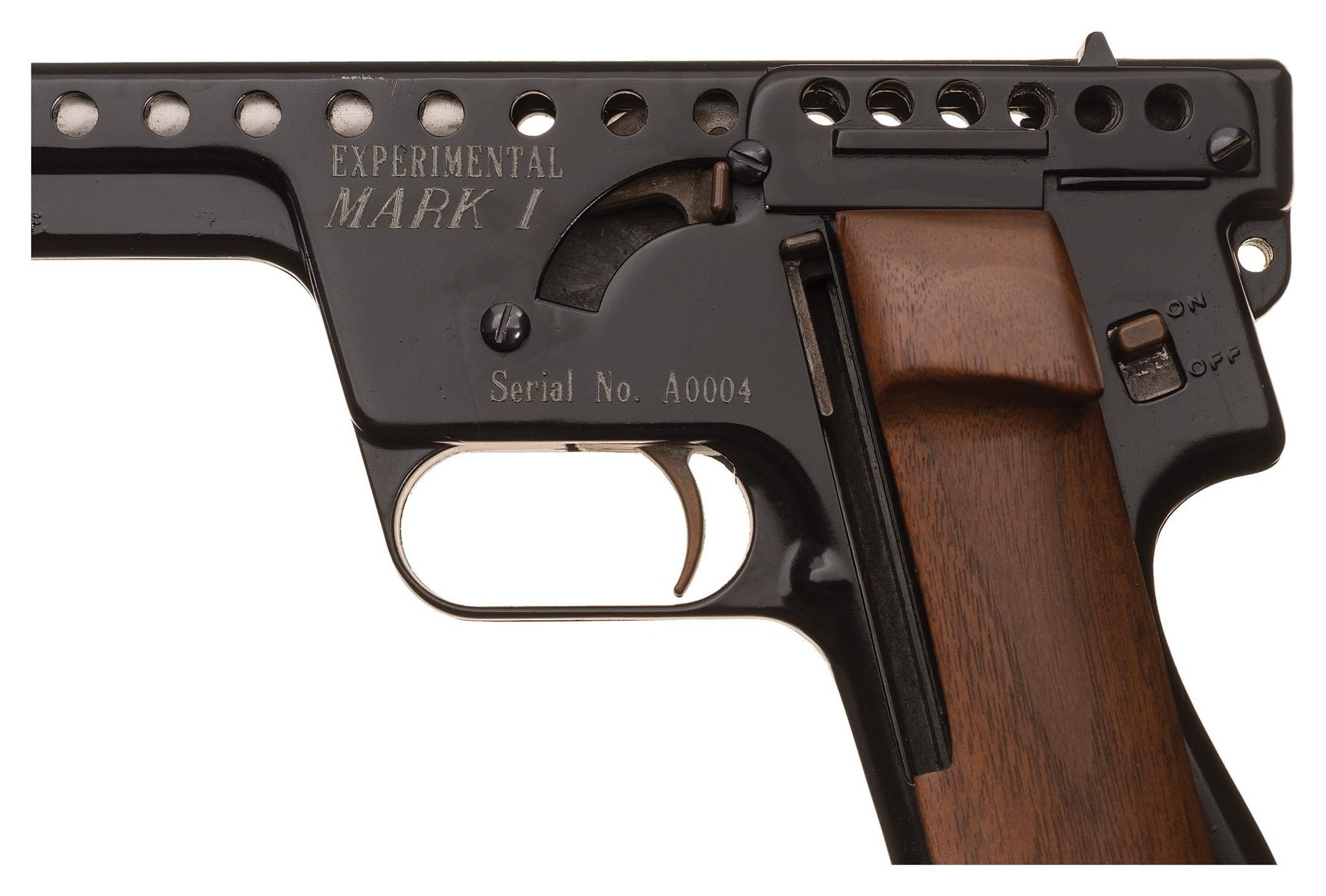 Figure 6 — The left side of an "EXPERIMENTAL / MARK I" pistol: the two engraved lines ahead of the hammer and the serial below. The fire controls have darkened to a brassy patina, which Rock Island records on…