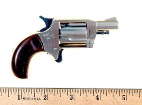Figure 2 — A mini-revolver removed from a belt-buckle holster, shown against a rule, from the FBI Law Enforcement Bulletin (public domain). The revolver is under five inches long, and the buckle that hides it…