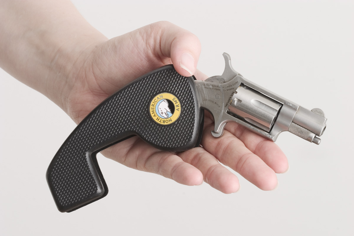 Figure 3 — An NAA mini in .22 LR fitted with the folding holster grip. The grip's front face covers the trigger stud when folded, so the gun can ride on a belt clip. Unfolded, as here, it gives a full hand a …