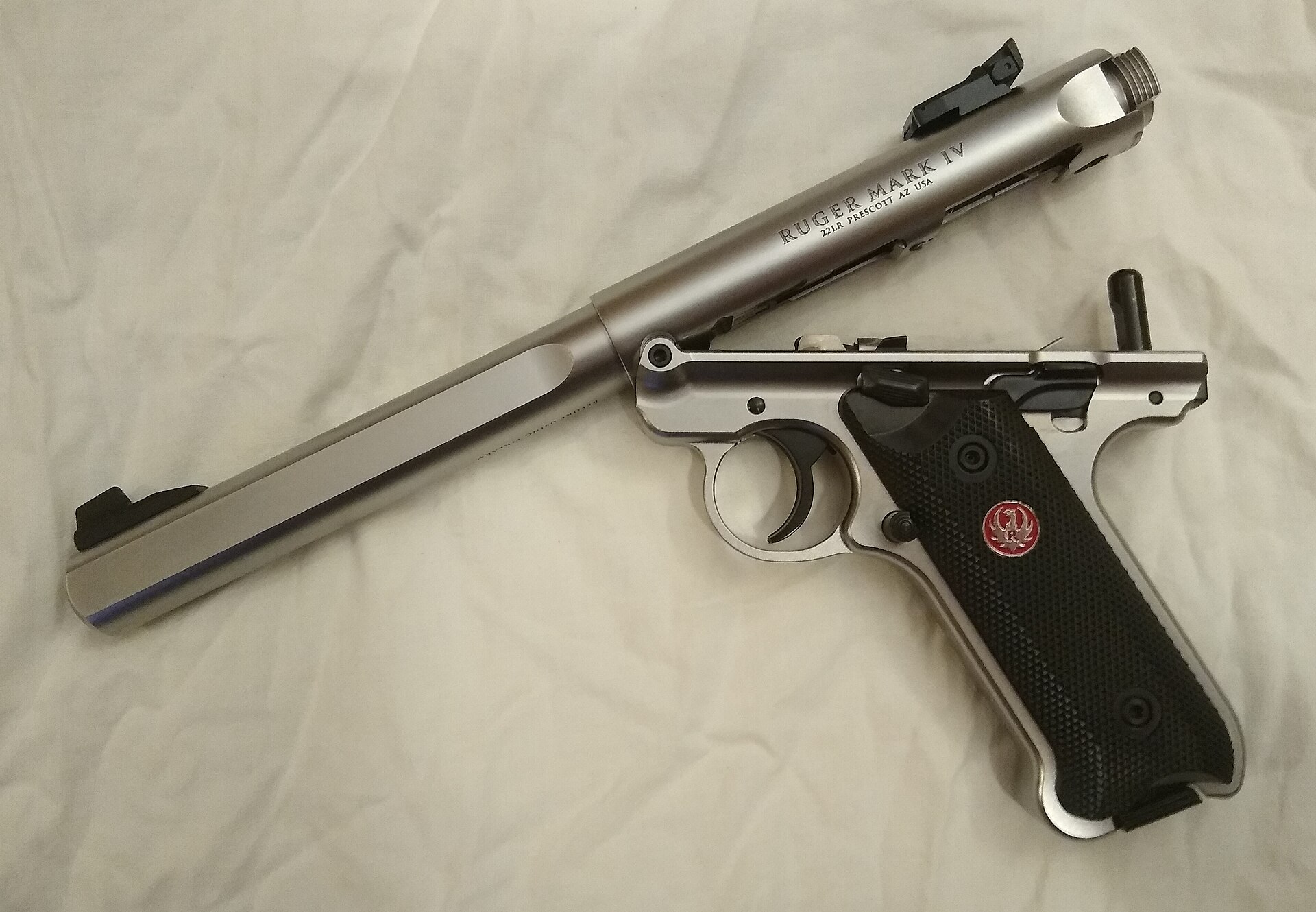 Figure 4 — A stainless Mark IV opened for cleaning: the takedown button at the top rear of the frame has been pressed and the barrel/receiver assembly has pivoted up at the rear on its front pivot. The bolt s…