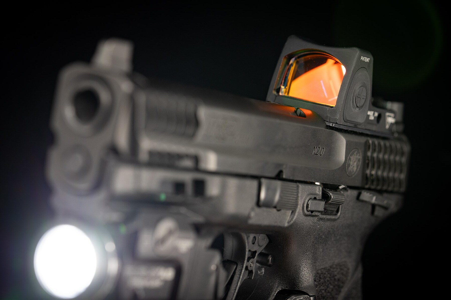 Figure 7 — A Streamlight weapon light lit, on a pistol that also carries a slide-mounted red dot. The light's beam is the one thing on a pistol that can be seen from the target's side — which is the whole of …