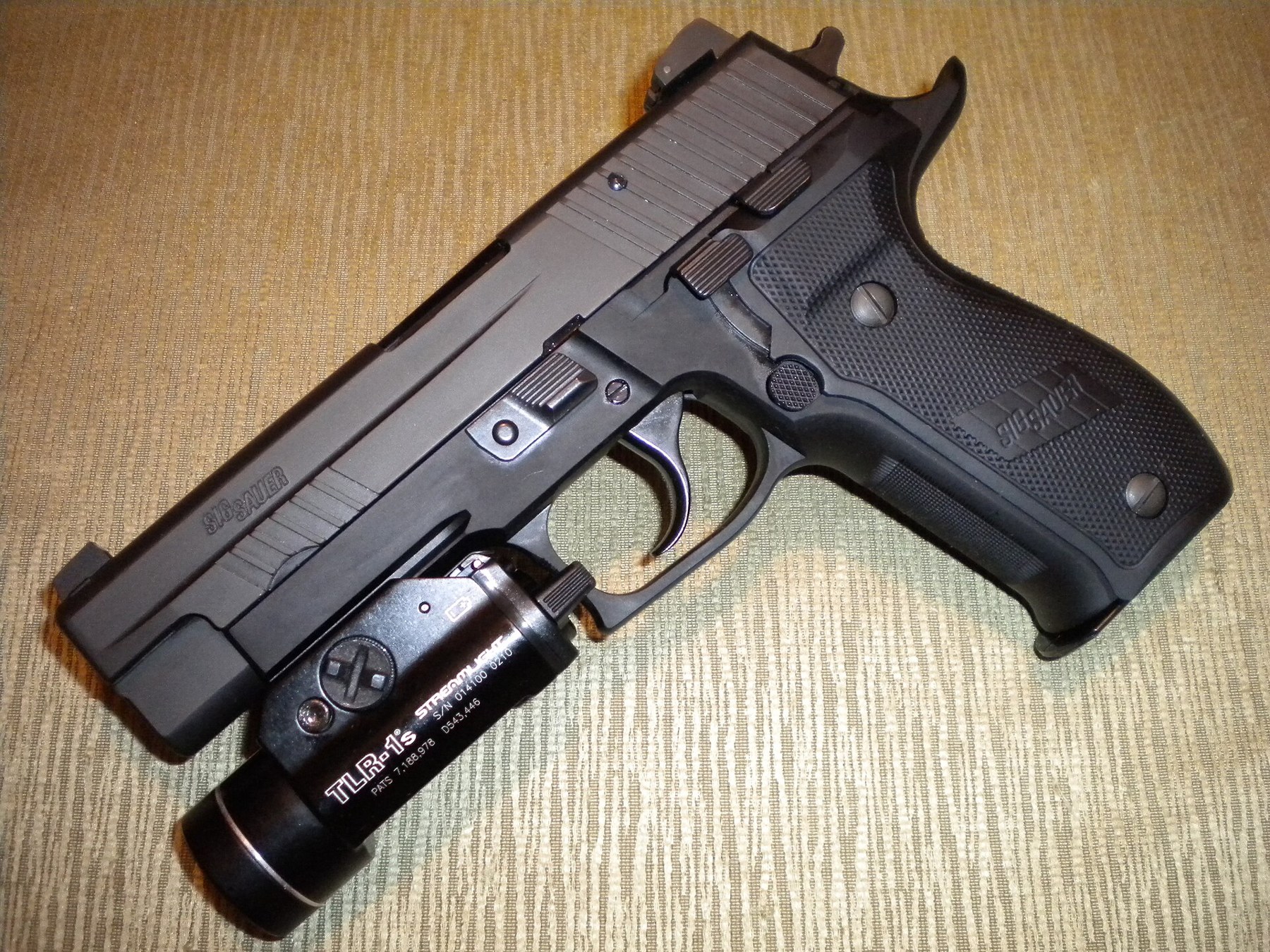 Figure 6 — A SIG P226 with a Streamlight TLR-1s mounted on its rail. The TLR-1s is the strobe-equipped sibling of the TLR-1 HL fitted to the pistol documented here; the body, rail clamp and rear paddle switch…