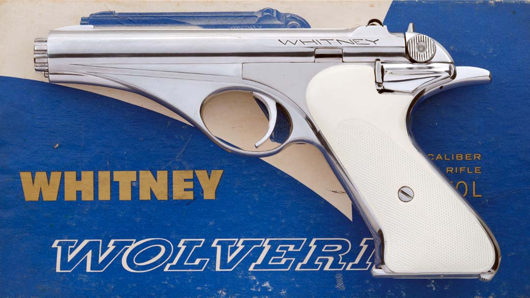 Figure 3 — A professionally bright-polished Whitney Firearms Inc. pistol with white grips in the "Whitney / Wolverine" box, offered by Rock Island Auction in May 2026 (lot 4097/1561; the photograph is matched…