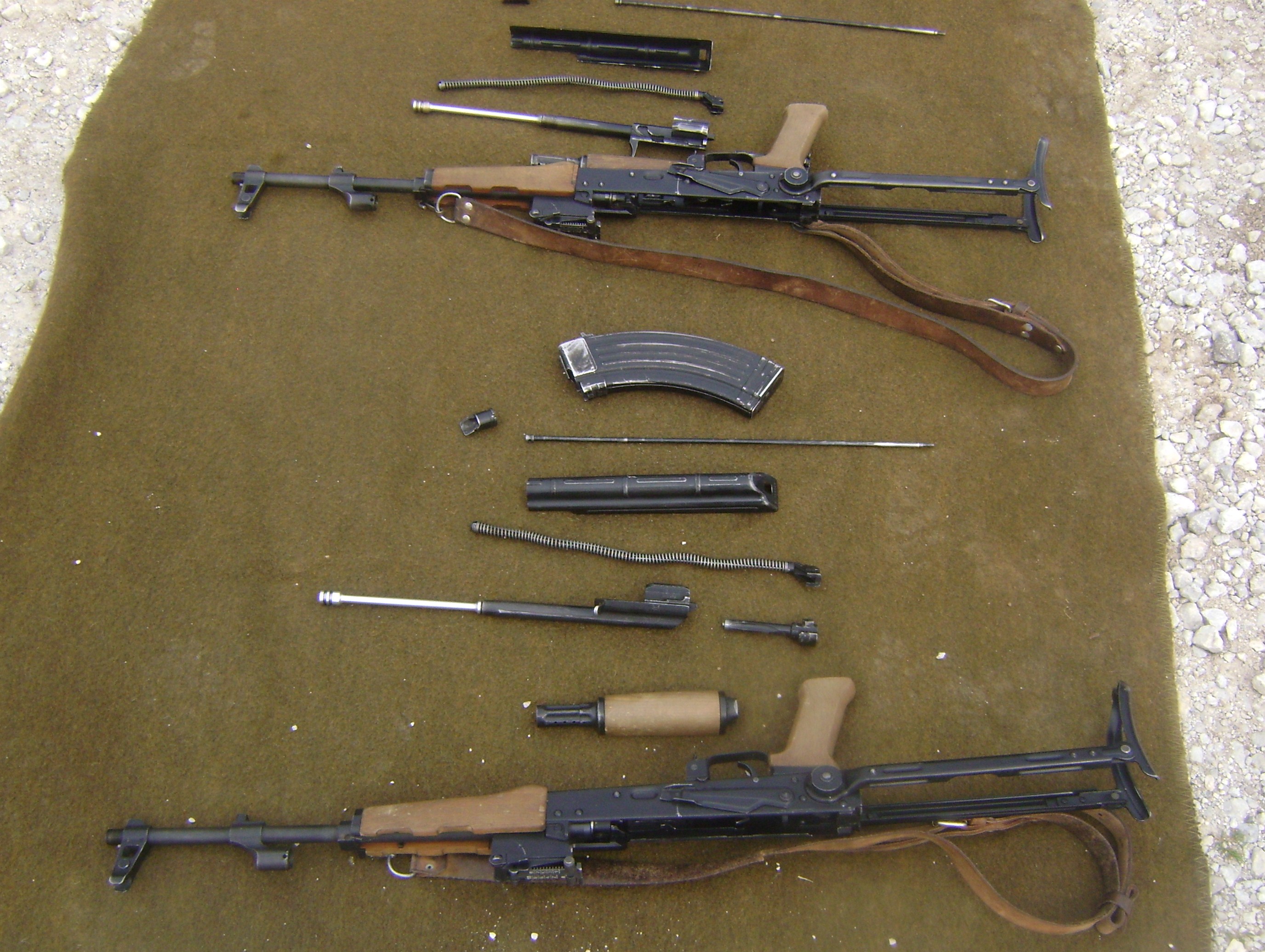 Figure 4 — An AK field-stripped to its main groups. Reading a rifle properly means getting the top cover off: the trunnion, the rivets from the inside, and the barrel's chamber end are where the answers are.