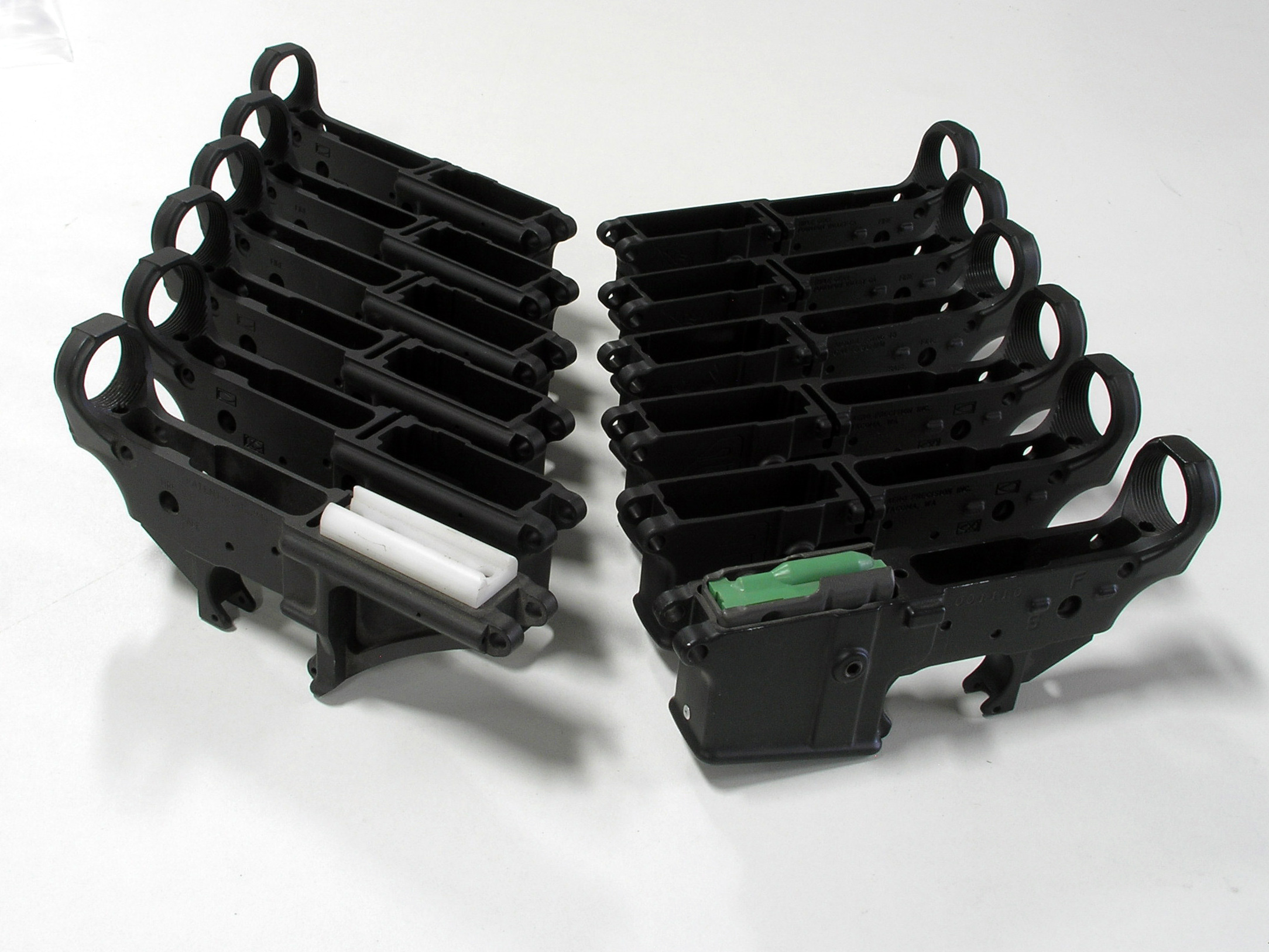 Figure 2 — Stripped lower receivers in quantity. Mechanically these are interchangeable shells; legally each one is a firearm and each carries its own serial number.