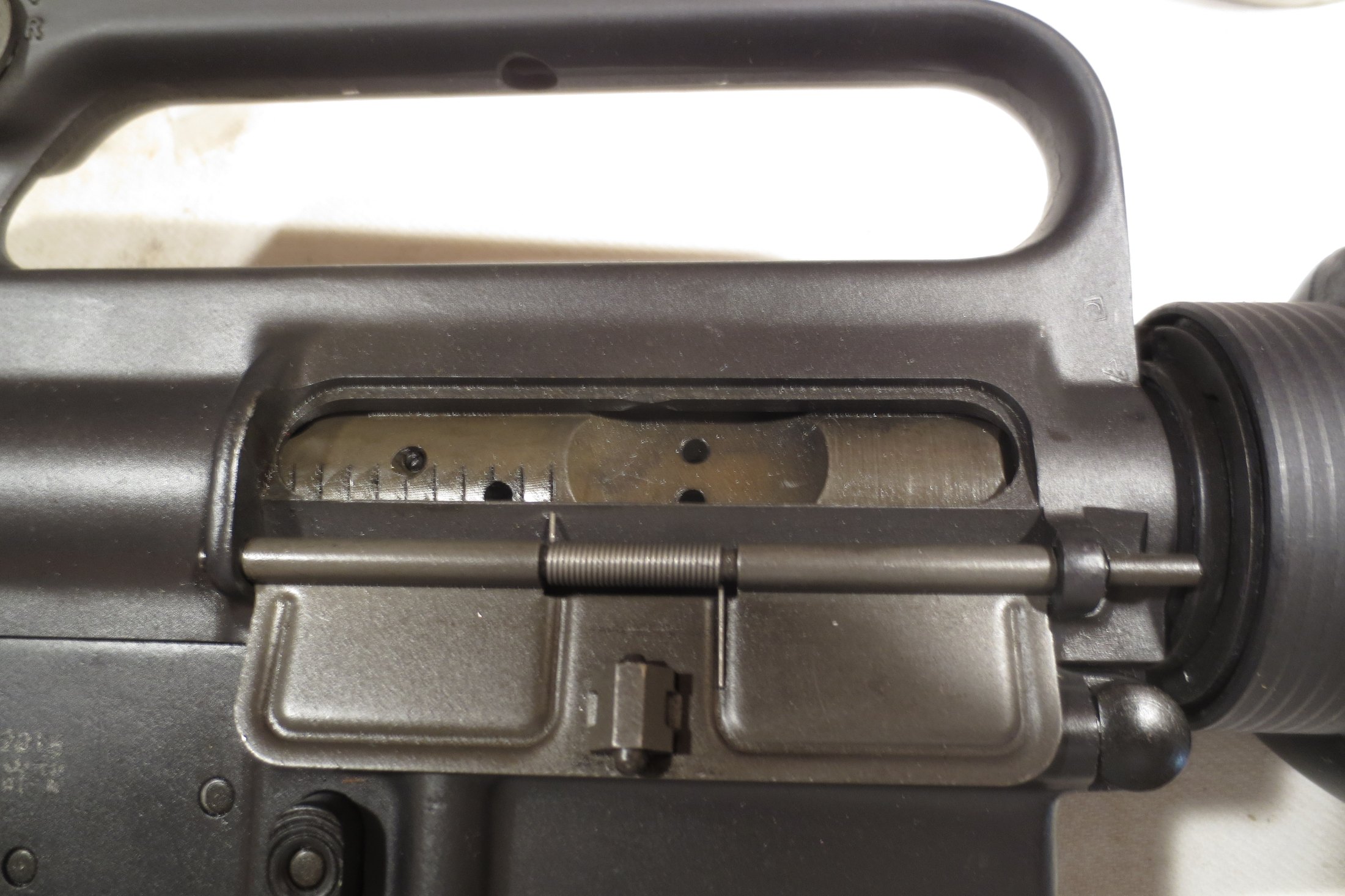 Figure 2 — The ejection port and forward assist of an M16-pattern rifle. The forward assist exists to push a reluctant bolt into battery; it is not a remedy for a dirty chamber, and using it to force a round …
