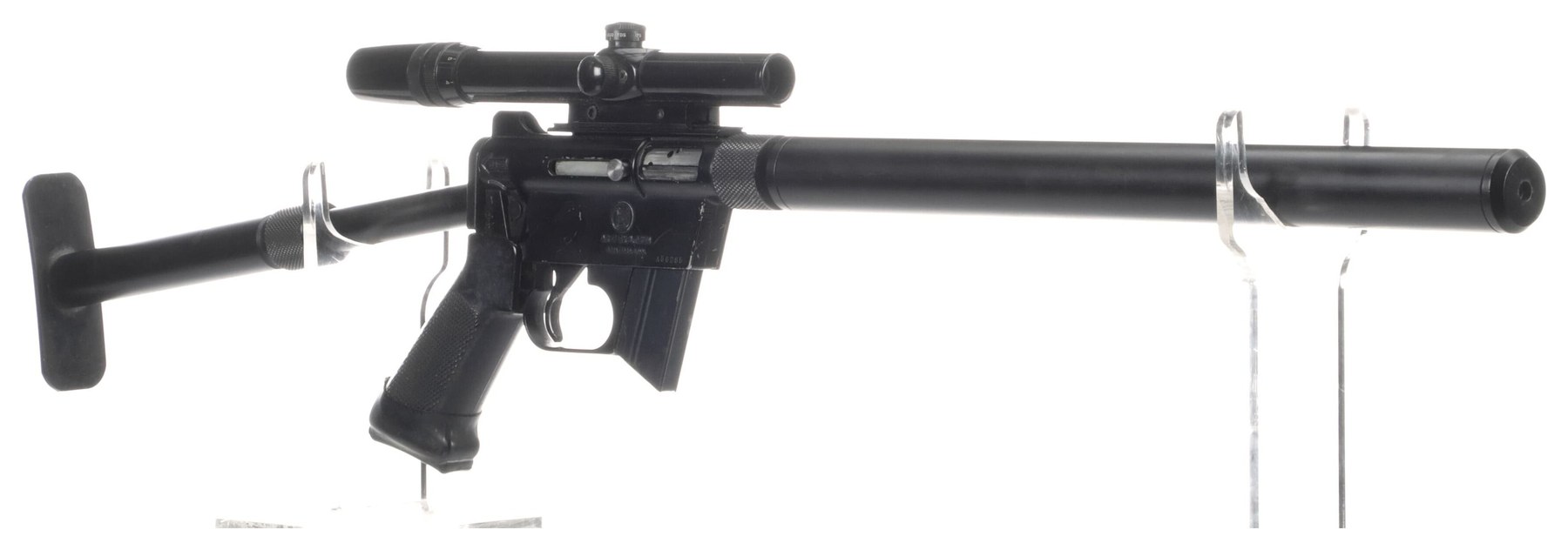 Figure 5 — A Charter Arms AR-7 fitted with aftermarket parts of the kind sold for the rifle from the 1960s on: a folding stock with a pistol grip, a full-length barrel shroud and a scope. Such parts give up t…