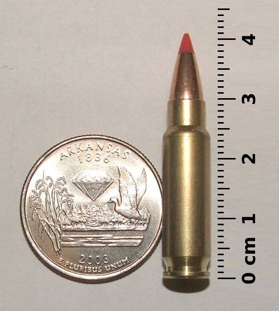 Figure 2 — The cartridge against a US quarter with a centimetre scale. The scale is the point — this is a cartridge sized like a pistol round and shaped like a rifle round.