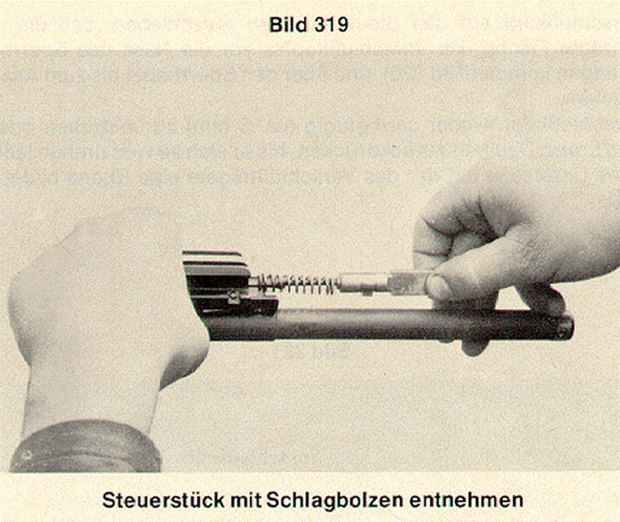 Figure 7 — Bolt strip, step two: the control piece is rotated to free the firing pin, and comes out of the carrier with the pin and its spring.