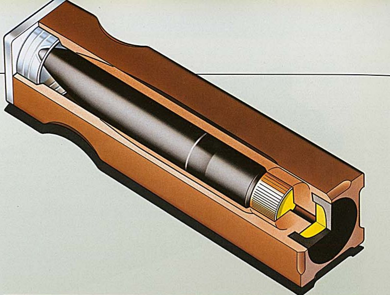 Figure 5 — Dynamit Nobel's cutaway of the caseless round, from the G11 brochure: the square propellant body moulded around the bullet, the plastic cap at the front, and the primer and booster at the base. Sou…