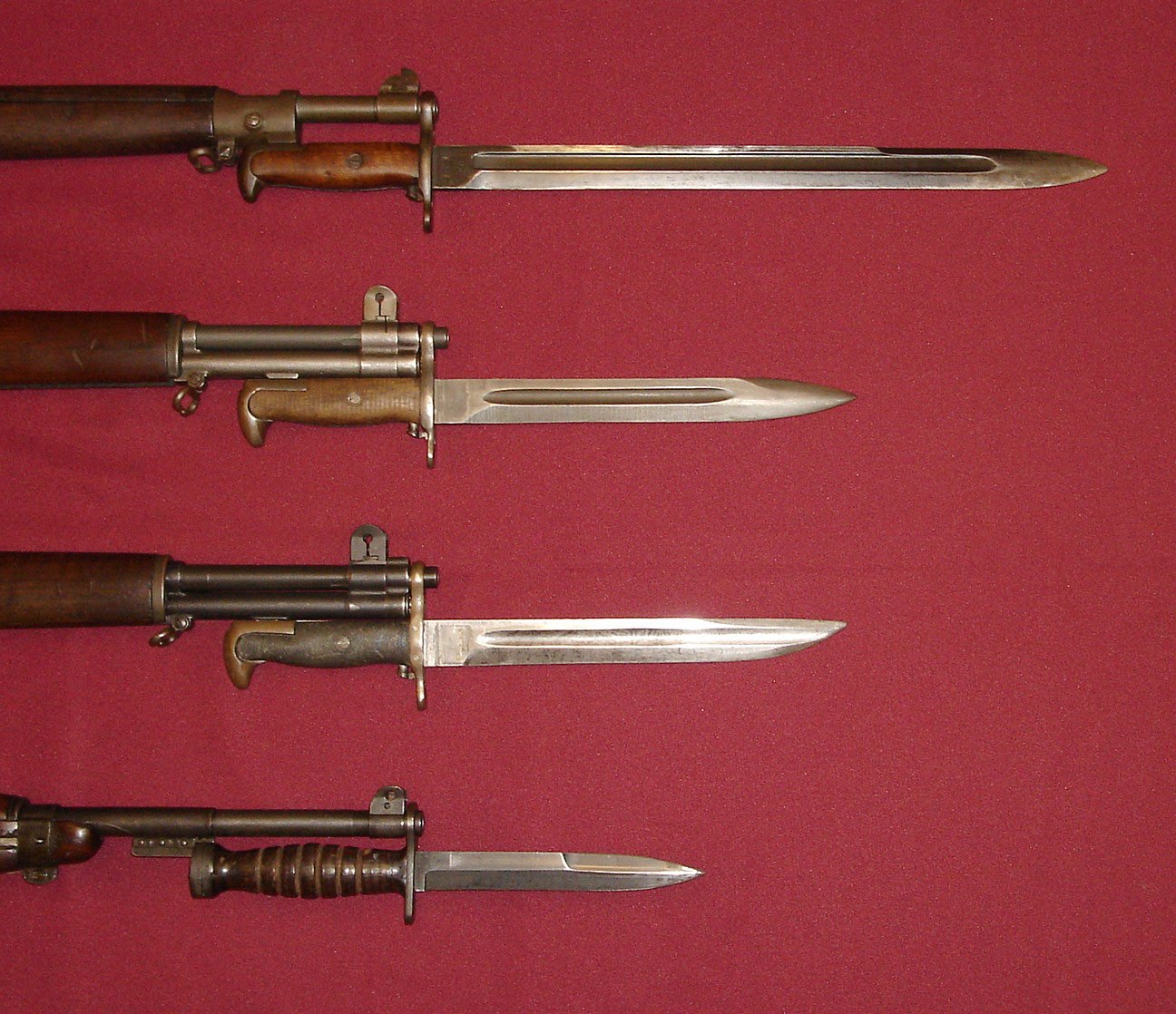Figure 7 — Second World War American bayonets, left to right as mounted: the M1905 (a blued example), the M1, a bowie-point converted M1905, and the M4 carbine bayonet for comparison. The M4 does not fit the …