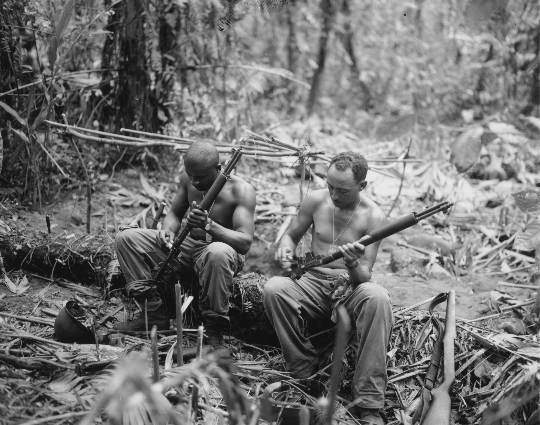 Figure 1 — Sergeant John C. Clark and Staff Sergeant Ford M. Shaw of Company E, 25th Combat Team, 93rd Infantry Division, clean their rifles in a bivouac area on Bougainville on April 4, 1944. — Photograph: L…