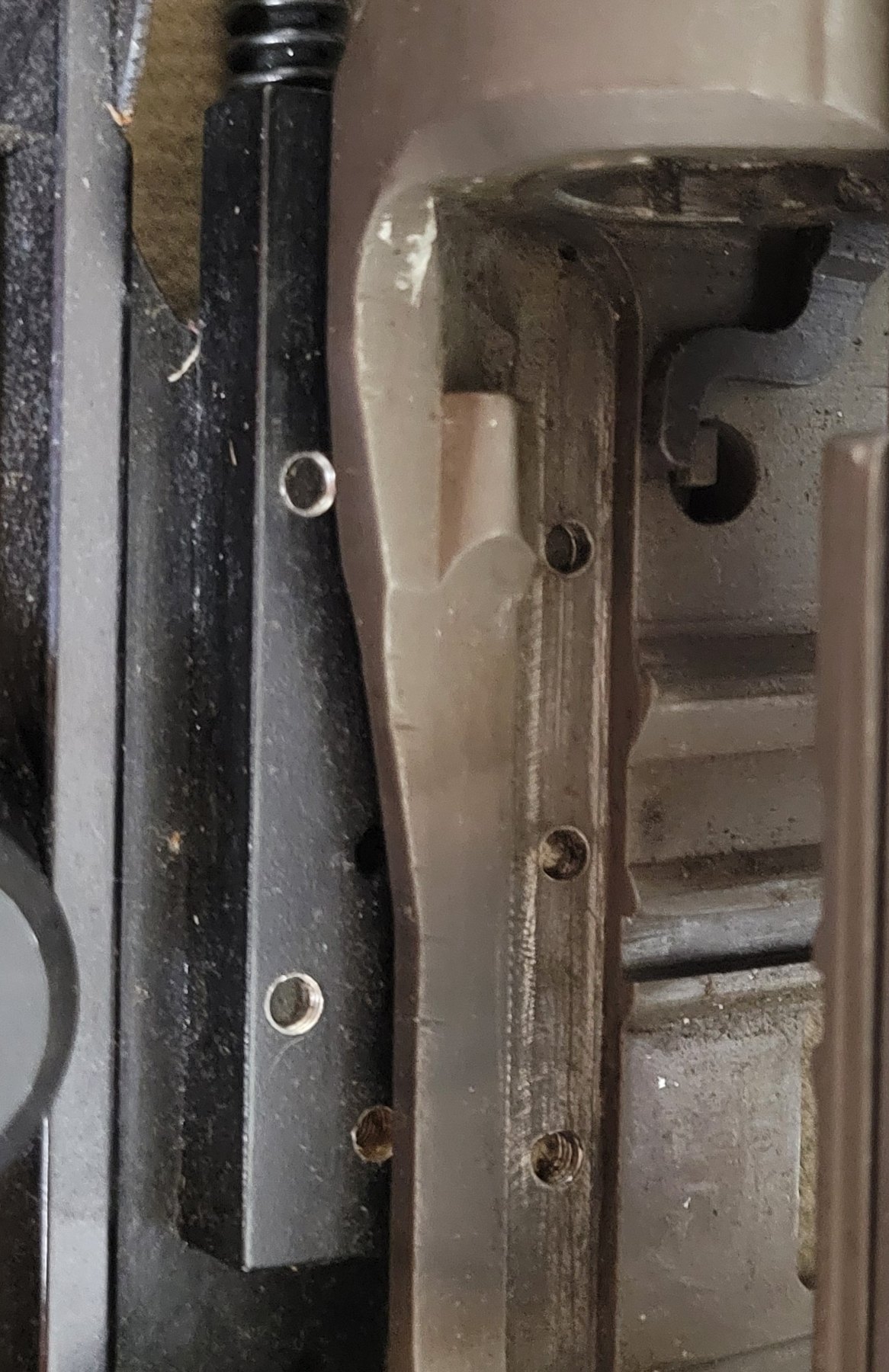 Figure 4 — The left receiver wall with the scope mount removed. Three tapped holes run along the wall; the mount's bar lies alongside with its matching holes. The lower two holes clearly show threads. There a…