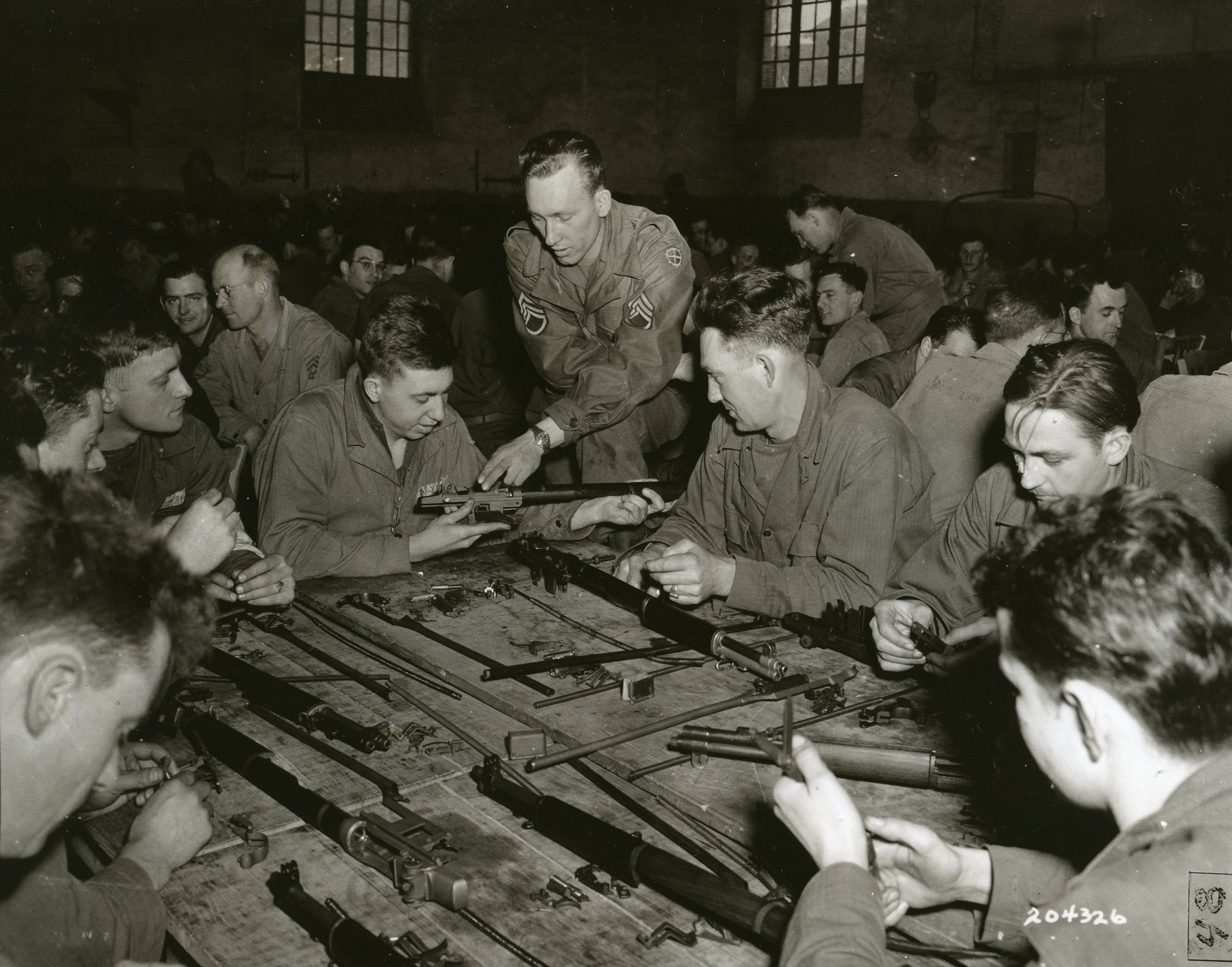 Figure 1 — A Medal of Honor recipient, Staff Sergeant Junior J. Spurrier, teaching care of the M1 at the Ground Forces Training Center in Fontainebleau, France, in March 1945. Field stripping was something ev…