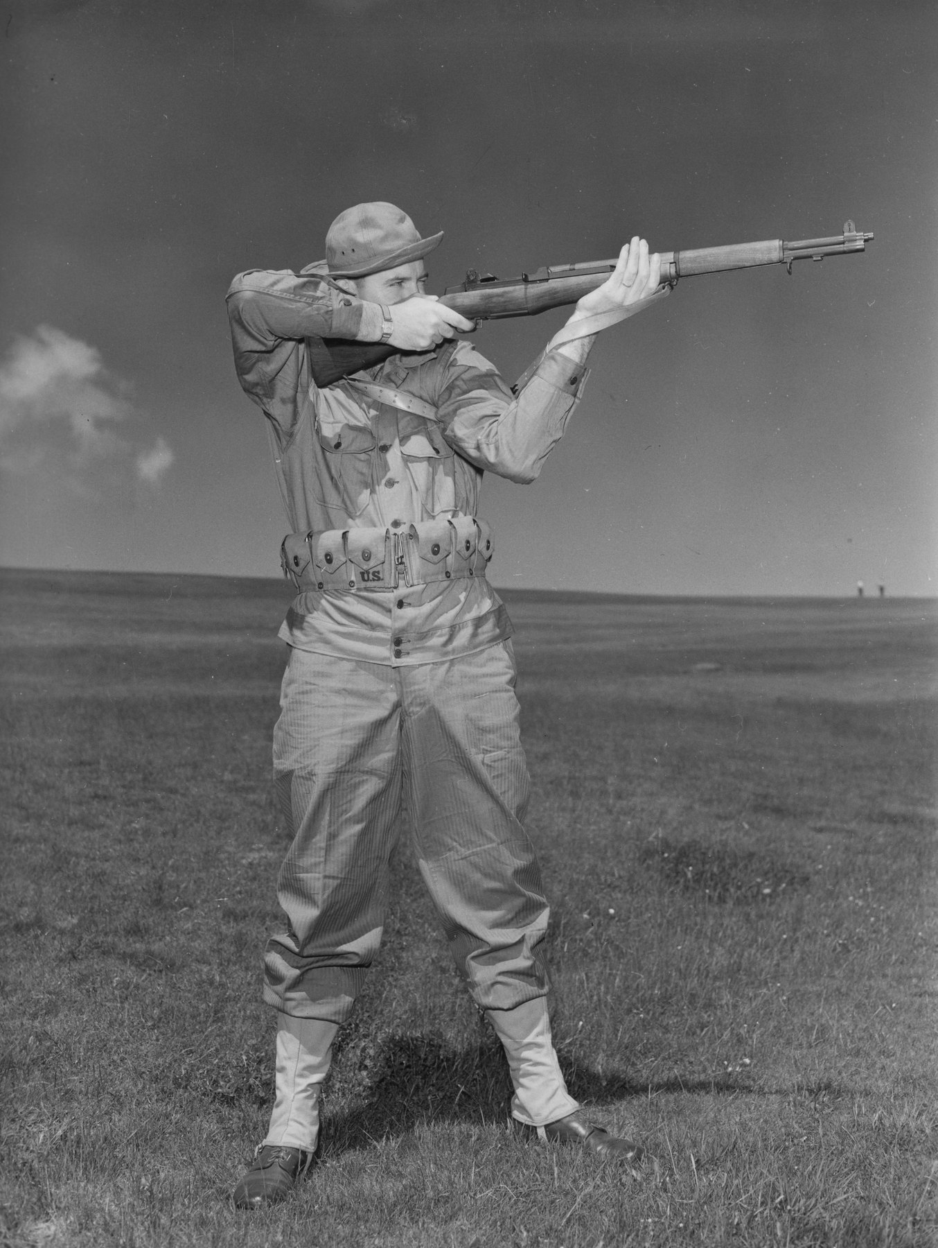Figure 6 — A soldier posed for a 1943 training photograph showing standing position — wearing the M1923 cartridge belt with its ten pockets. — Photograph: Cpl. Howard Warner, 21st Signal Service Company, U.S.…