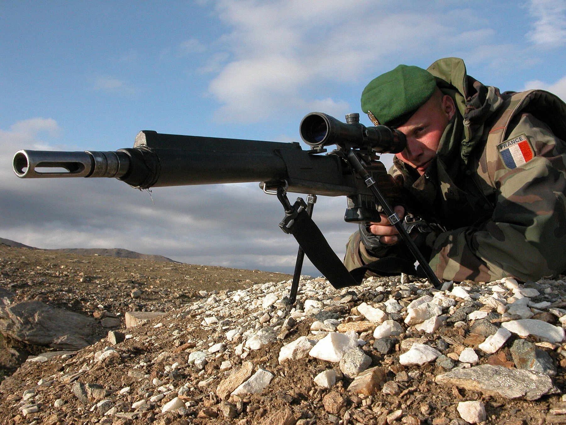 Figure 6 — A marksman of the 2e régiment étranger d'infanterie with an FR-F2 in Afghanistan in 2005, the uploader's own photograph. Thermal sleeve, slotted muzzle device, bipod yoke and a fixed-power scope. P…