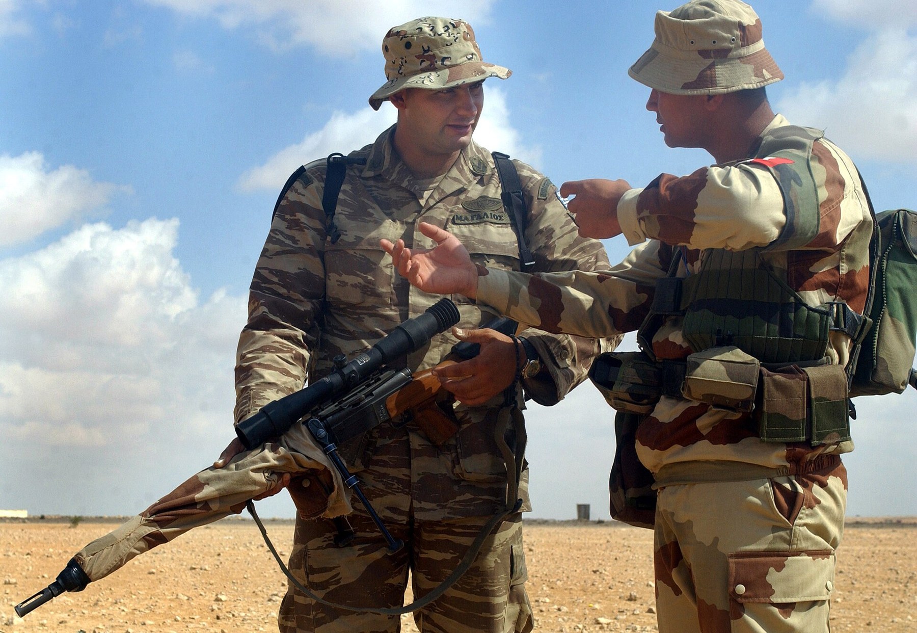 Figure 5 — A French marksman explains his FR-F2 to a Greek marksman at the small-arms range outside Mubarak Military City, Egypt, during Exercise Bright Star 01-02, 16 October 2001. The barrel sleeve wears a …