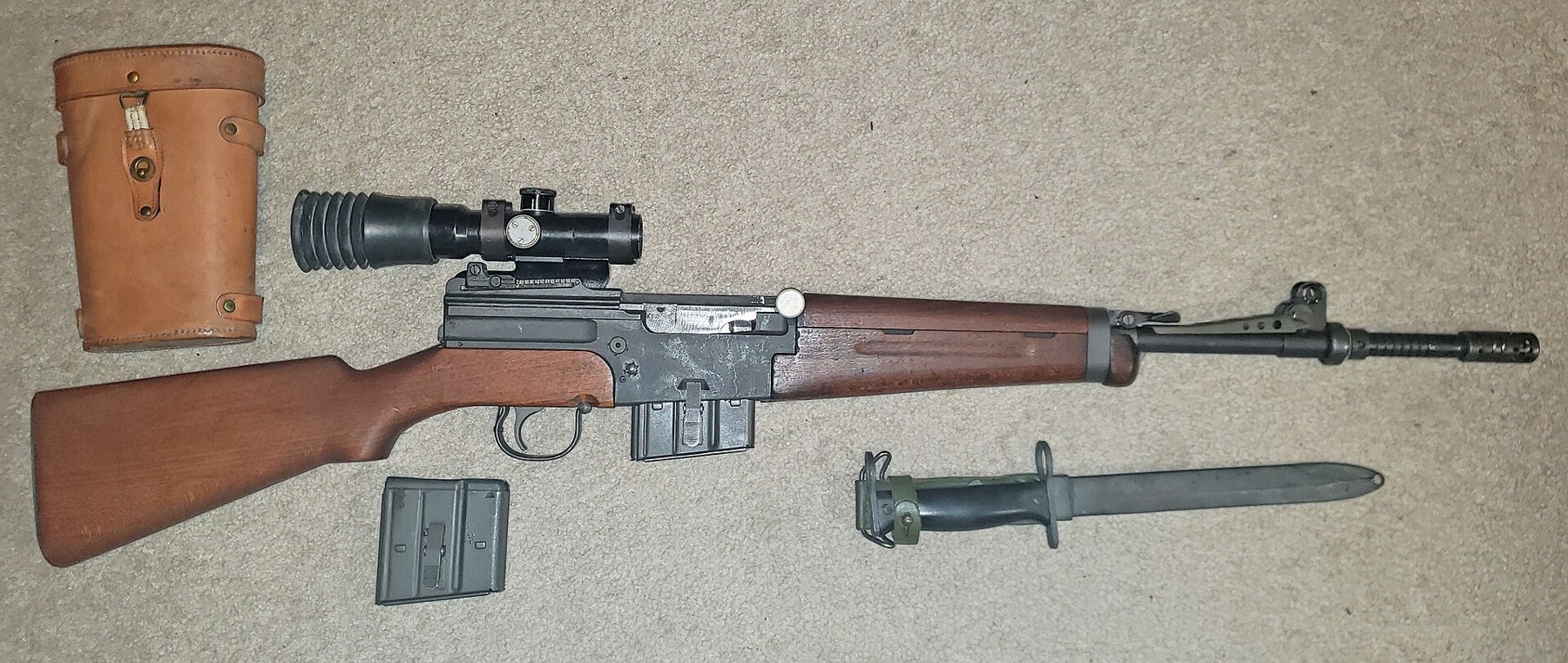 Figure 14 — A MAS 49/56 semi-automatic rifle with its APX scope, the scope's leather case, a magazine and the bayonet, from a private collection. The scope rides on a mount on the left of the receiver. Photogr…
