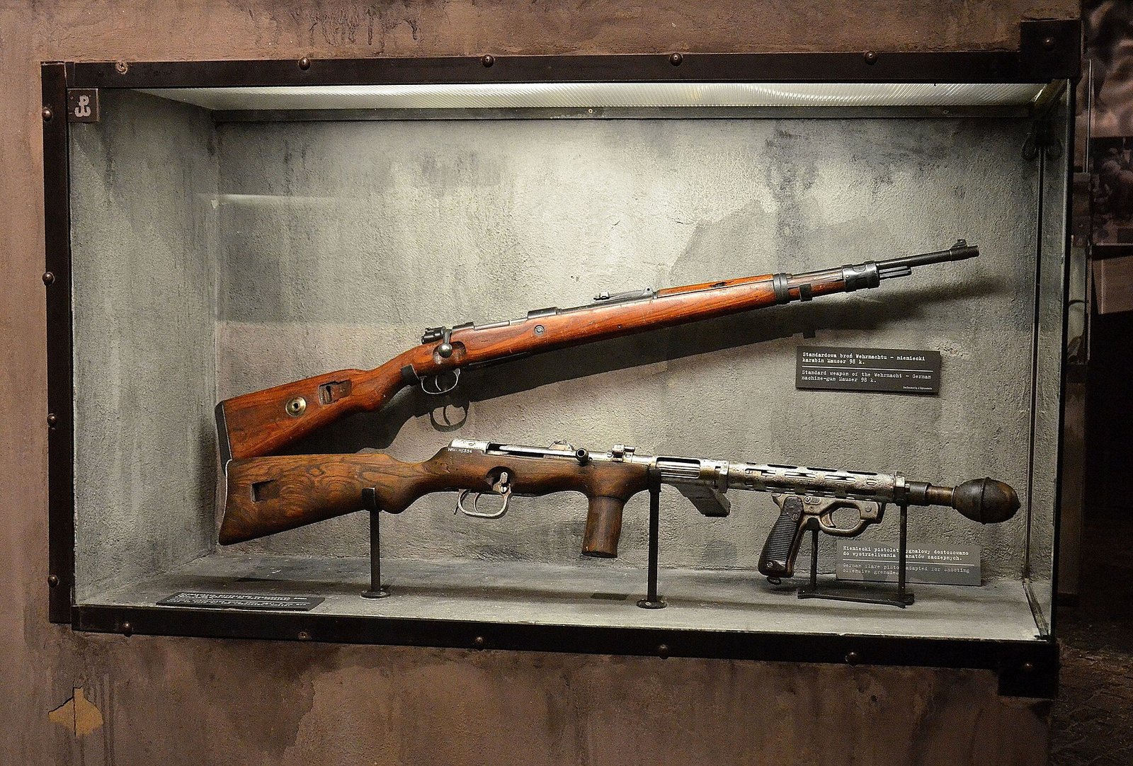 Figure 3 — An Erma EMP on museum display. The commercial predecessor to the MP 38 is a wooden-stocked weapon with a perforated barrel jacket and a forward wooden grip, and it sold widely on the export market …