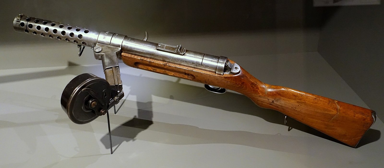 Figure 2 — An MP 18 with the Trommelmagazin 08 snail drum fitted. This is Hugo Schmeisser's design, and it is the weapon that earns his name its place in submachine gun history. The drum was adapted from the …