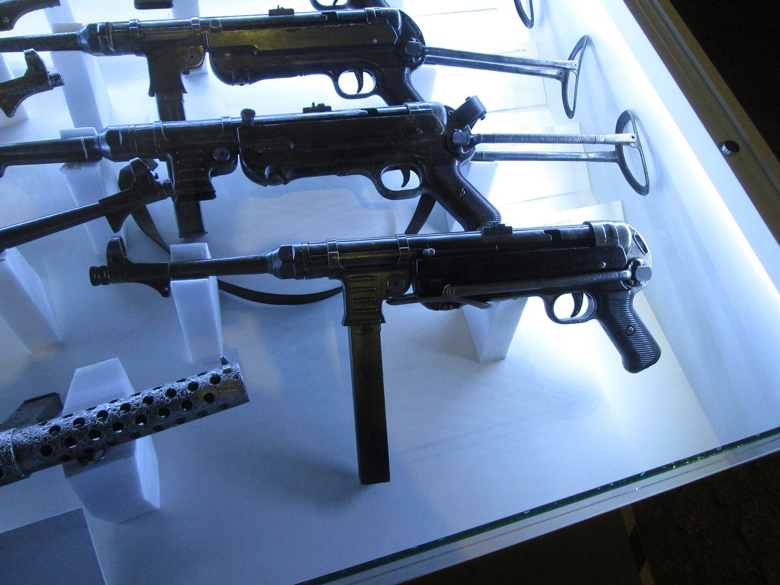 Figure 6 — Three MP 40s in a museum case. Weapons from different makers and different years are externally indistinguishable — which is the point of the manufacturing system, and the difficulty for anyone try…