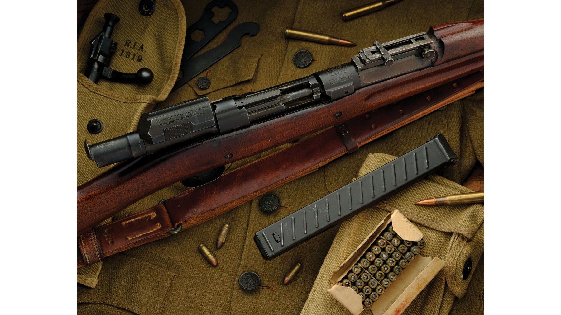 Figure 5 — The device in a Mark I, close up: the ribbed slide handle, the frame and the magazine latches behind a 40-round magazine. Rock Island Auction Company, 26 August 2023, lot 1336.