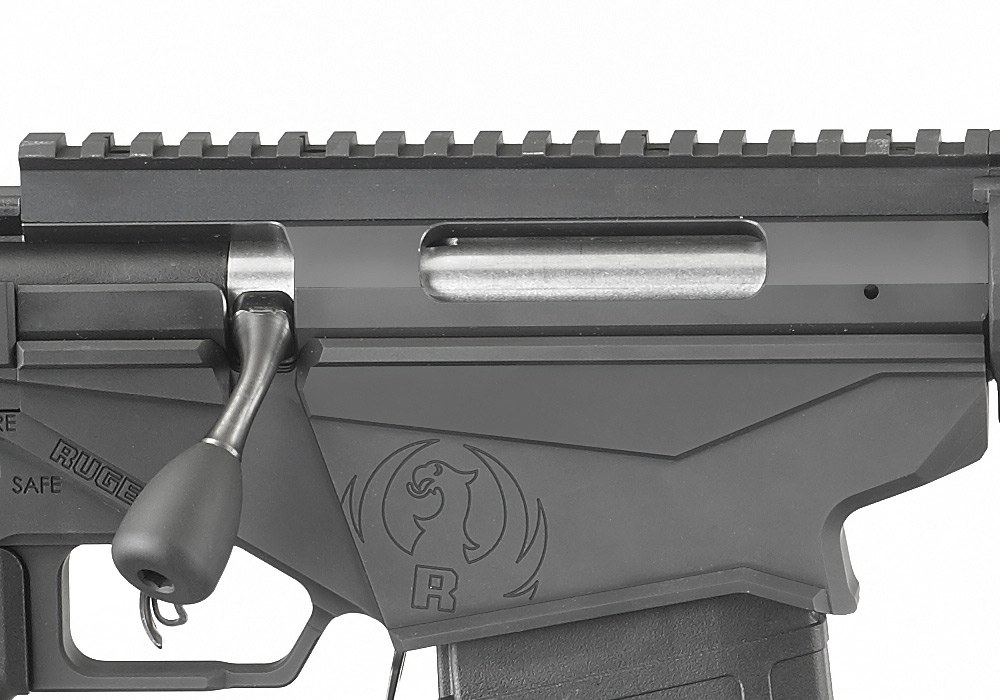 Figure 2 — The 2016 rifle's receiver from the right, bolt closed: the steel receiver with the Picatinny rail screwed to its top, the ejection port, the bolt handle, and the aluminium magazine well below with …