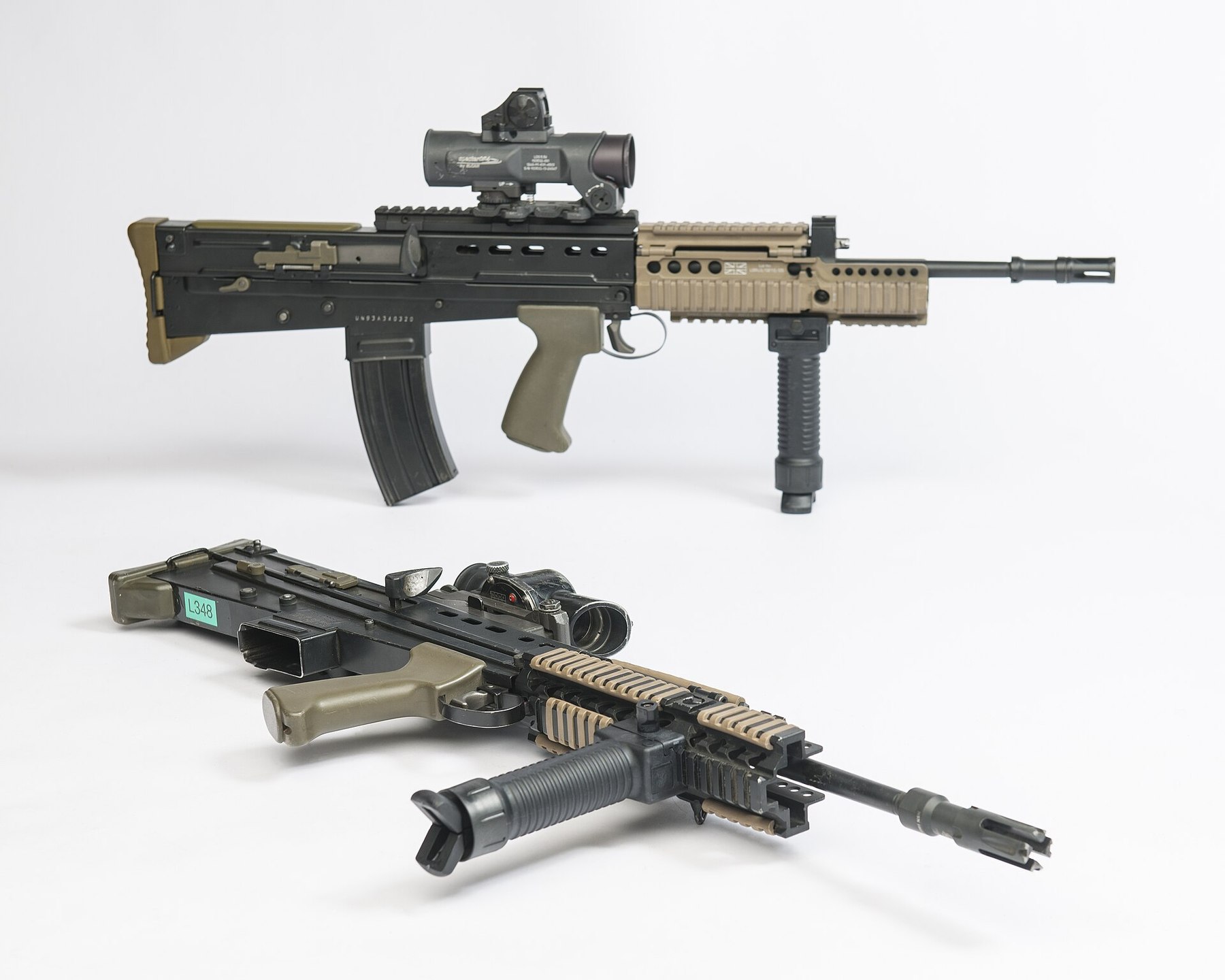 Figure 3 — Two SA80-A2 rifles. Behind, a rifle with an Elcan Specter carrying a small reflex sight on top, a tan rail fore-end and a vertical grip; in front, a rifle with a SUSAT, a Daniel Defense-pattern rai…