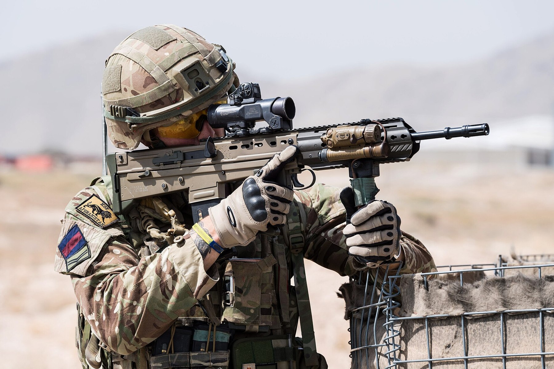 Figure 10 — A British soldier aims an L85A3 with optical sight and vertical grip in Afghanistan on Operation Toral, the post-2014 training mission. MOD photograph by Cpl Rebecca Brown, Open Government Licence …