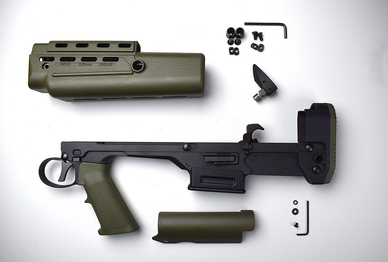 Figure 2 — The parts of an Aly & Kaufman AKB-23 "L85" lower kit: the bullpup lower receiver with its trigger linkage and butt, an L85-style pistol grip and handguard in green, a cheek piece, and the small par…