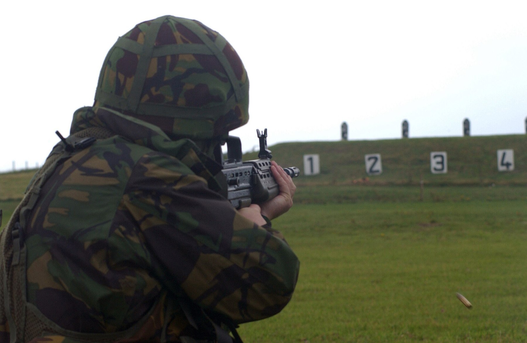 Figure 3 — A British soldier in a camouflage smock aims an SA80 at numbered targets on a range on Benbecula in the Outer Hebrides. US Air Force photograph by A1C Stacia M. Willis, public domain.