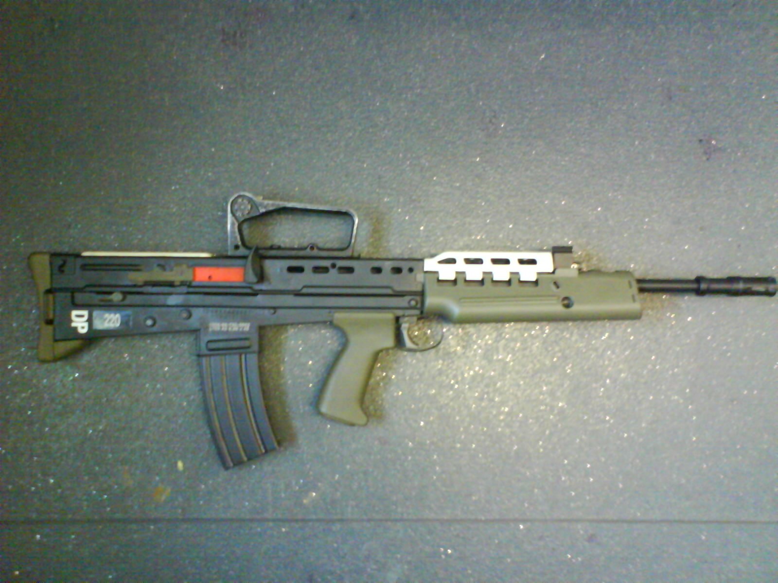 Figure 13 — A drill-purpose SA80, described by its photographer as an L103A2 made from an L98A2 cadet rifle: carrying-handle iron sight, foresight removed, no change lever, with a white drill marking on the ha…