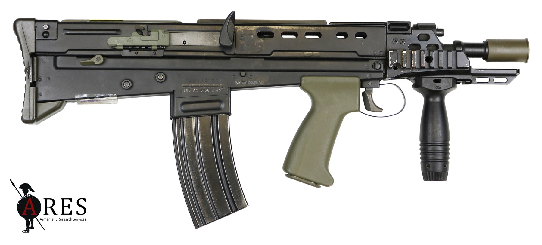 Figure 10 — An L22A2 carbine, right side, muzzle right: the short barrel and flash suppressor, the vented aluminium heat shield with rails at 3 and 6 o'clock, the H&K vertical foregrip, the A2 cocking handle, …